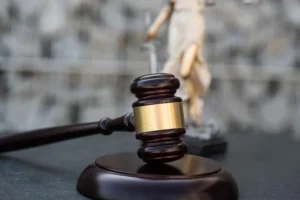 A wooden gavel on its sound block in front of a Lady Justice statue