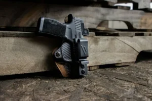 A handgun in a black holster resting on a weathered wooden plank