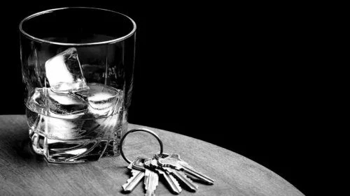 A glass of whiskey on ice next to a set of car keys