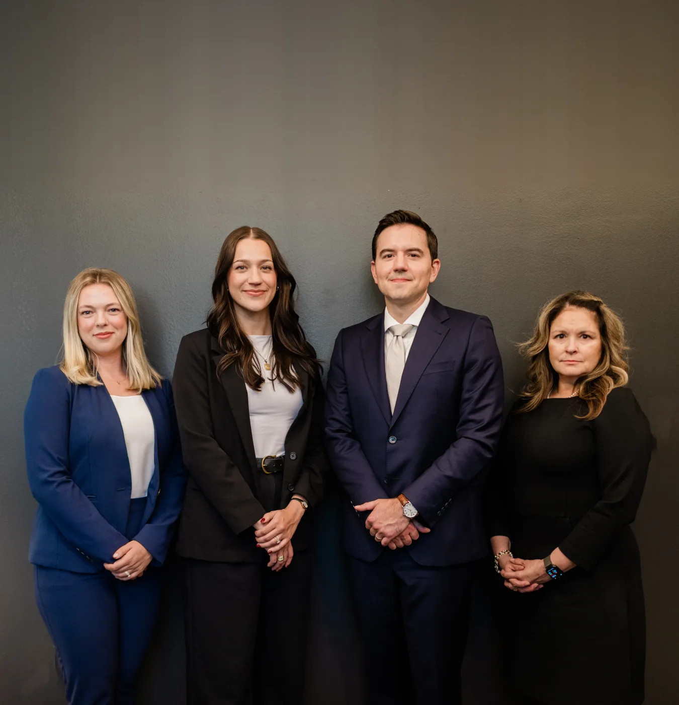 Four members of the firm's team standing together against a dark wall