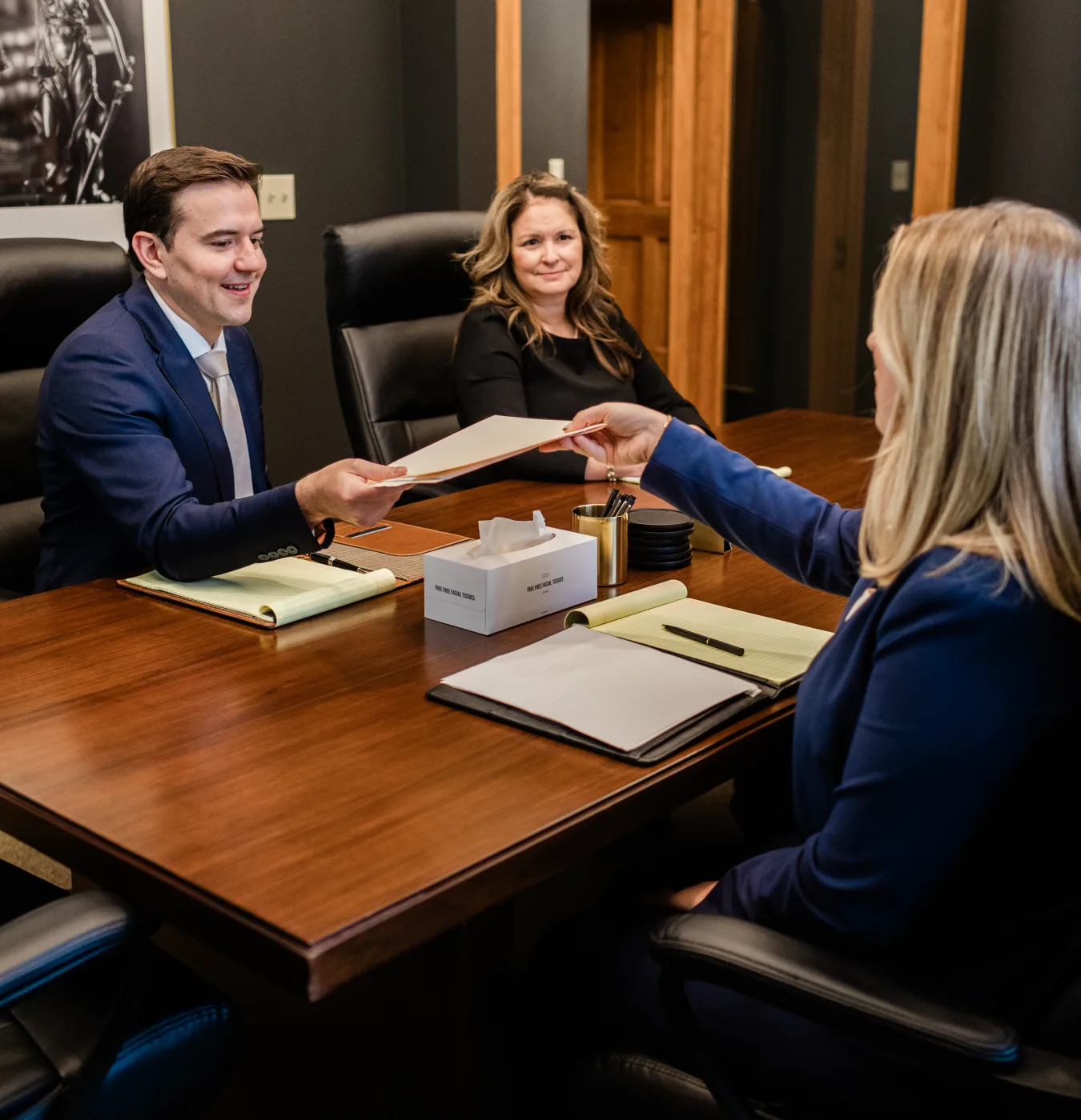 An attorney handing a document across the conference table to a colleague